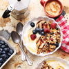 Frühstück mit Joghurt Beeren Nüssen und Kaffee auf rustikalem Tisch
