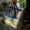 Person hebt Netzeinsatz mit Lebensmitteln aus Petromax Kühltasche in natürlicher Umgebung