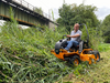 Mann bedient AS 1040 YAK 4WD XL Aufsitzschlegelmäher in dichtem Gras unter Brücke