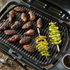 Weber Traveler Compact Gasgrill mit gegrillten Hähnchenteilen und Peperoni in natürlicher Umgebung