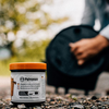 Petromax Pflegepaste vor unscharfem Hintergrund mit Person und Dutch Oven