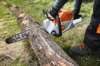 Person verwendet STIHL MSA 220 C-B Akku-Kettensäge zum Schneiden eines Baumstamms