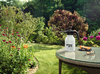 STIHL SG 11 Handspritzgerät auf Gartentisch umgeben von blühendem Garten
