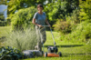 Frau mittleren Alters mäht Rasen mit STIHL RM 2 R Rasenmäher in einem sonnigen Garten