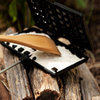 Petromax Waffeleisen auf Holzstamm mit Waffelteig und Holzspatel im Freien