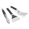 Weber Griddle Grillwerkzeug-Set mit Grillwender Grillzange und Grillschaber auf grünem Hintergrund