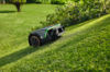 STIHL iMOW 4 EVO Mähroboter mäht autonom einen grünen Rasen in einem Garten