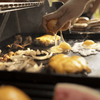 Person bereitet Eier und andere Speisen auf einer Weber CRAFTED Grillplatte im Freien zu