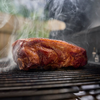 Saftiges geräuchertes Fleisch auf einem Grillrost umhüllt von Rauch