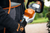 Person bedient Stihl HSA 130 T Akku-Heckenschere mit sichtbarem Akkustatus im Freien