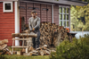 Mann benutzt STIHL Kettensäge zum Holzschneiden vor rotem Schuppen