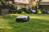 STIHL iMOW 6 Mähroboter mäht Rasen vor einem Einfamilienhaus mit Garten