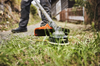 Stihl FS-KM AC C 26-2 Sense in Aktion beim Trimmen von Gras nahe einem Holzhaus