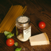 O'Donnell Käsereibe-Aufsatz auf einem Glas mit Parmesan, umgeben von Tomate, Basilikum und Spaghetti