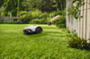STIHL iMOW 4 Mähroboter mäht selbstständig einen grünen Rasen in einem schönen Garten