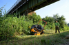 Mann bedient ferngesteuerten Aufsitzmäher AS 940 Sherpa 4WD RC unter einer Brücke