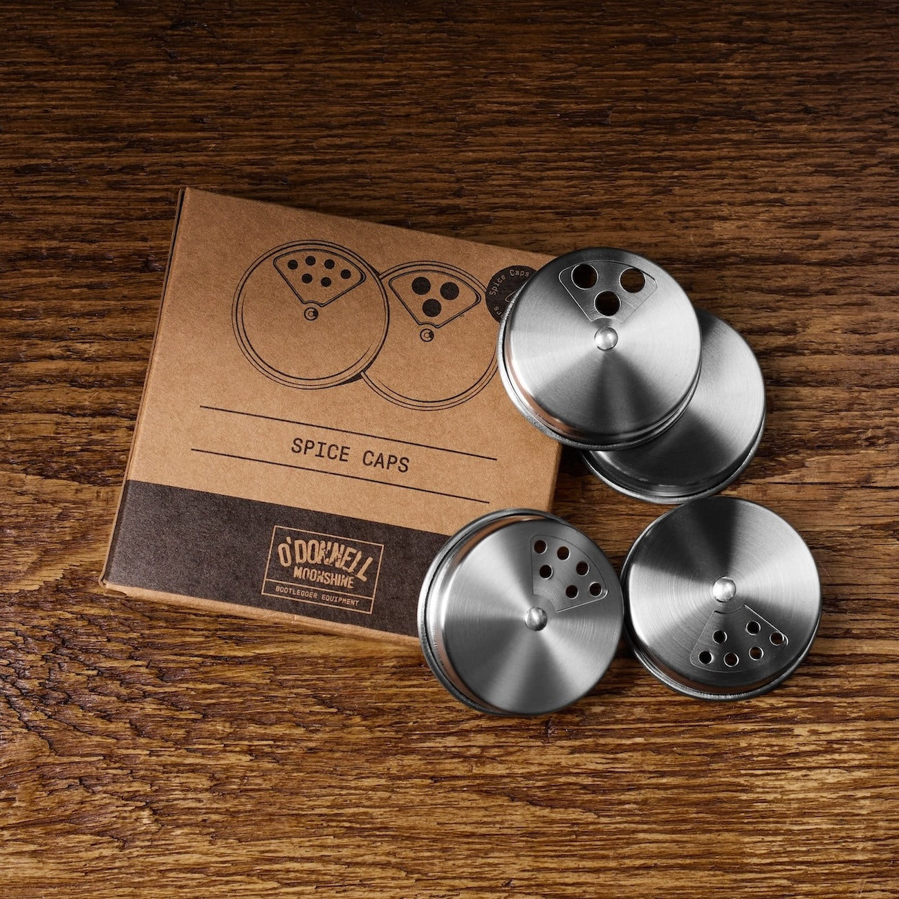 Metallene Gewürzaufsätze von O'Donnell Moonshine auf Holztisch neben Verpackung