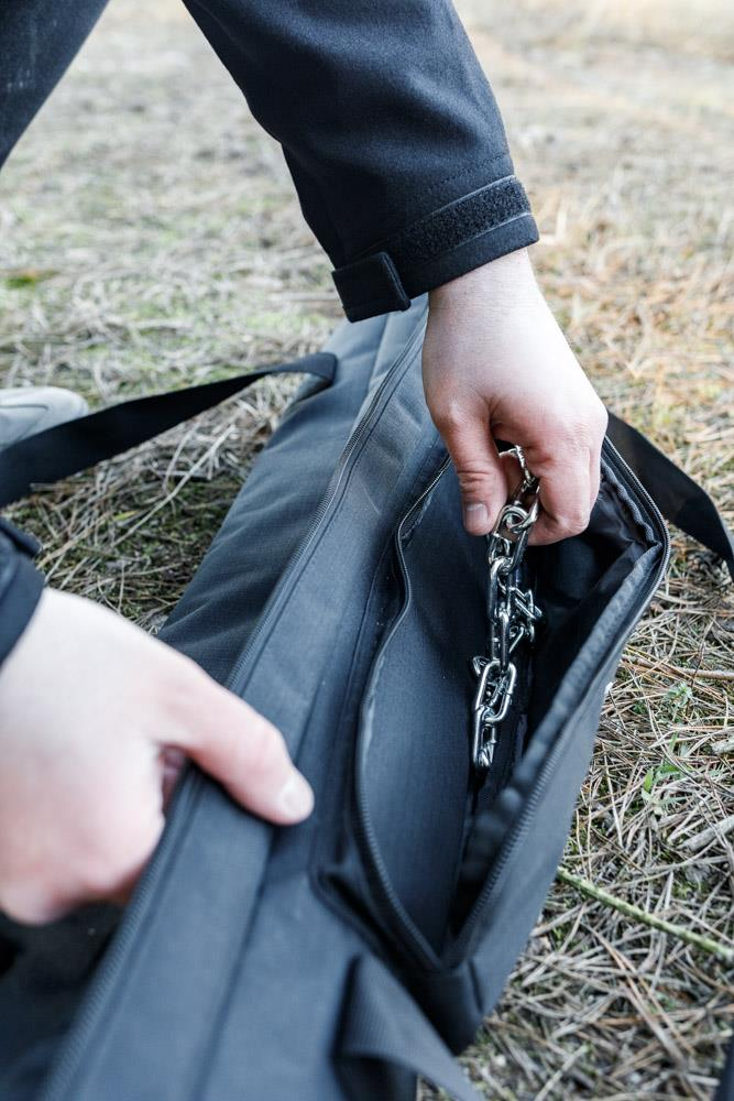 Person öffnet robuste Transporttasche für Dreibein im Freien