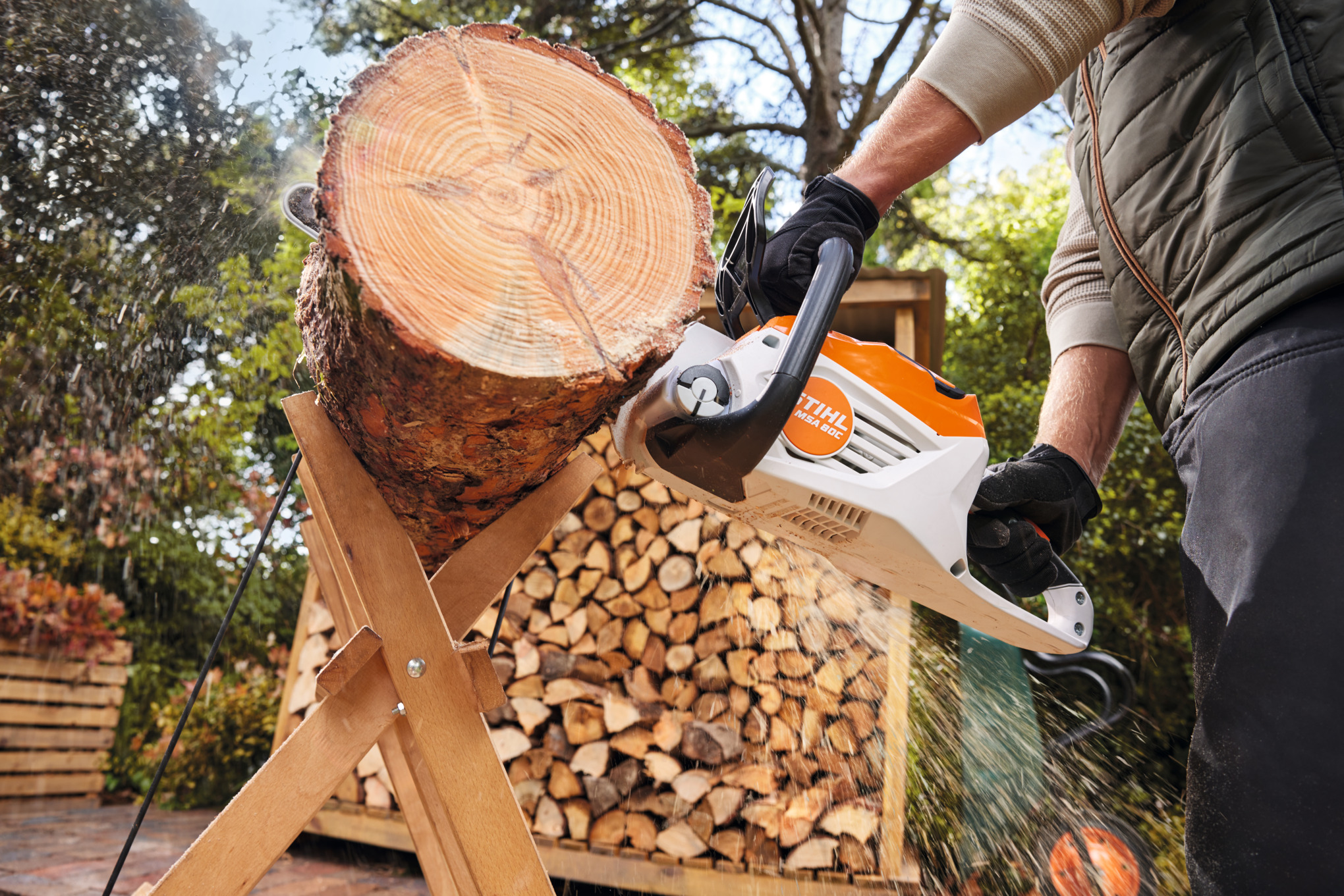 Person verwendet STIHL MSA 80 C-B Akku-Motorsäge zum Sägen eines Baumstamms im Freien