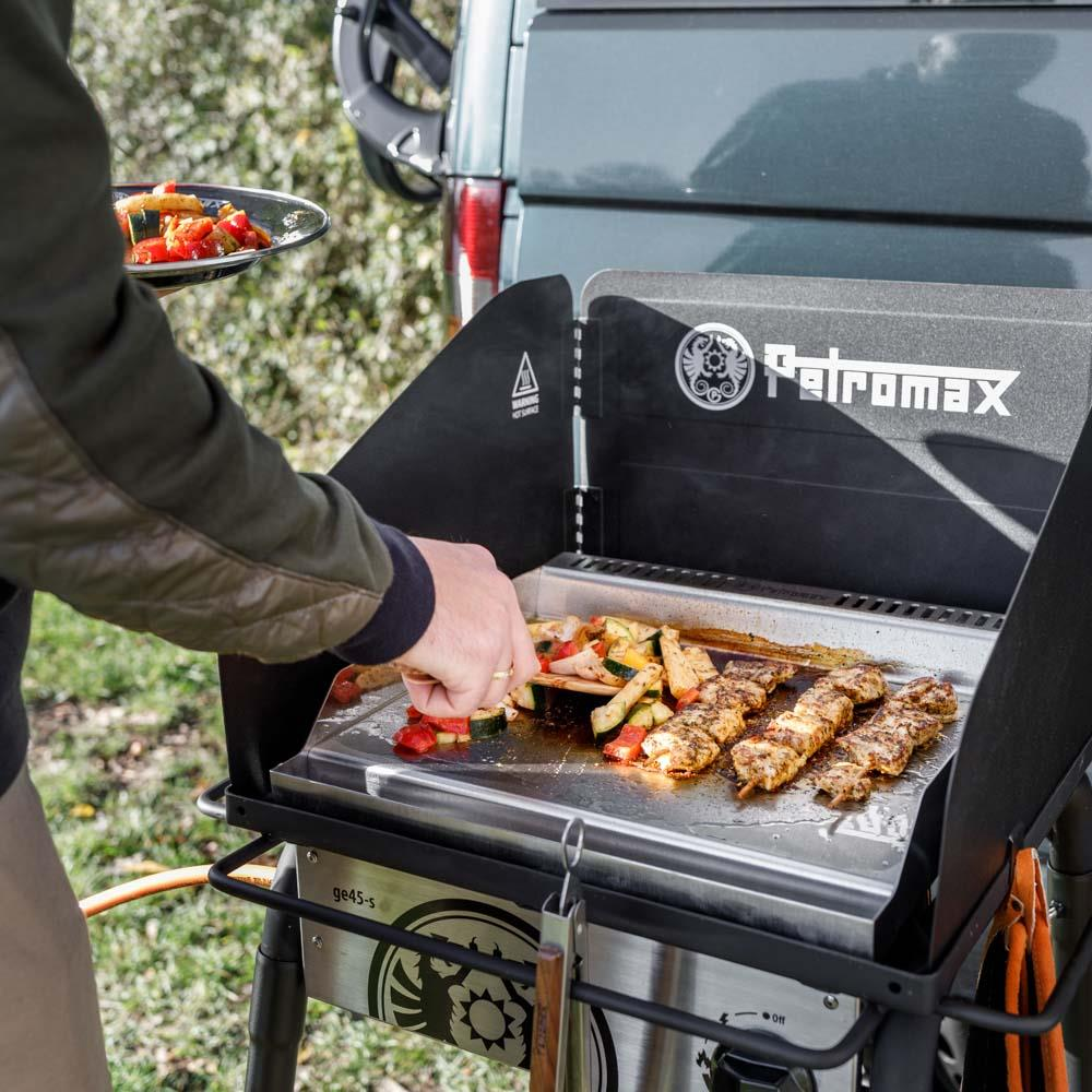 Person grillt Fleisch und Gemüse auf Petromax Plancha Grillplatte im Freien