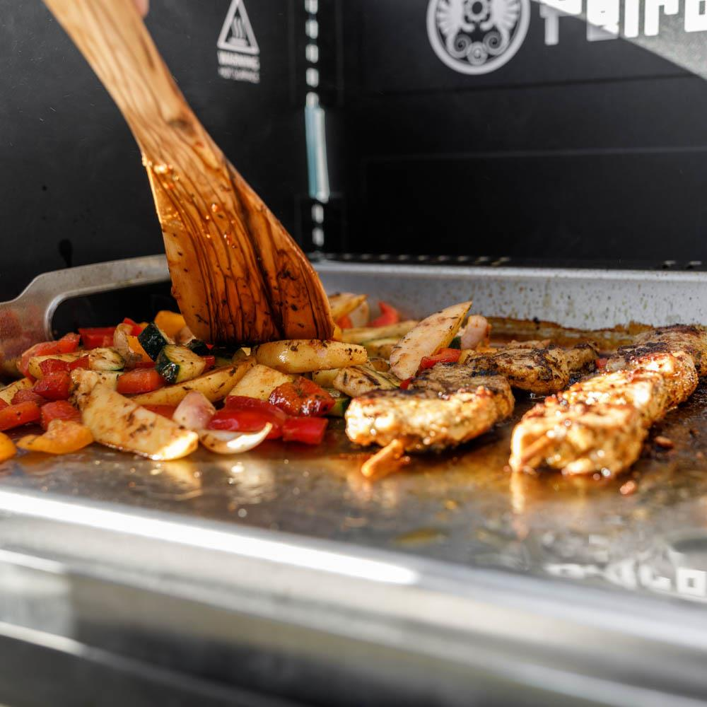 Plancha Grillplatte auf Petromax Gastisch mit gebratenem Fleisch und Gemüse im Freien