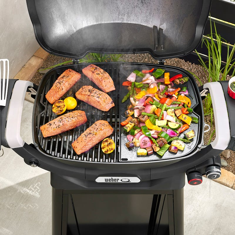 Weber Q Grill mit Lachs und buntem Gemüse auf Grillplatte im Freien