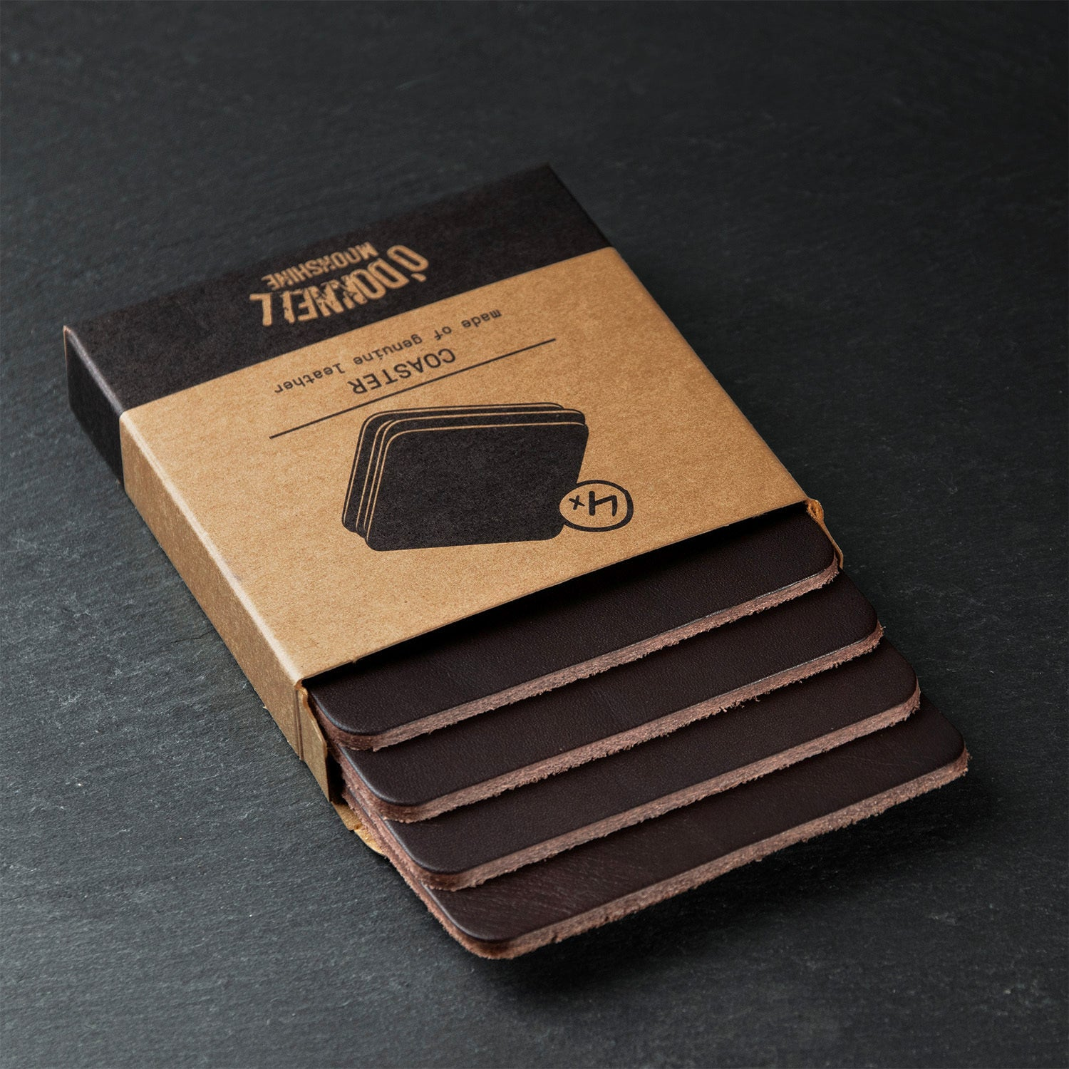 Vier dunkelbraune Ledercoaster von O'Donnell, teilweise in brauner Verpackung
