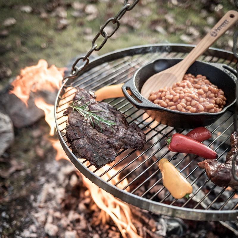 Petromax Hänge-Rost mit Steak und Bohnen über Lagerfeuer im Freien