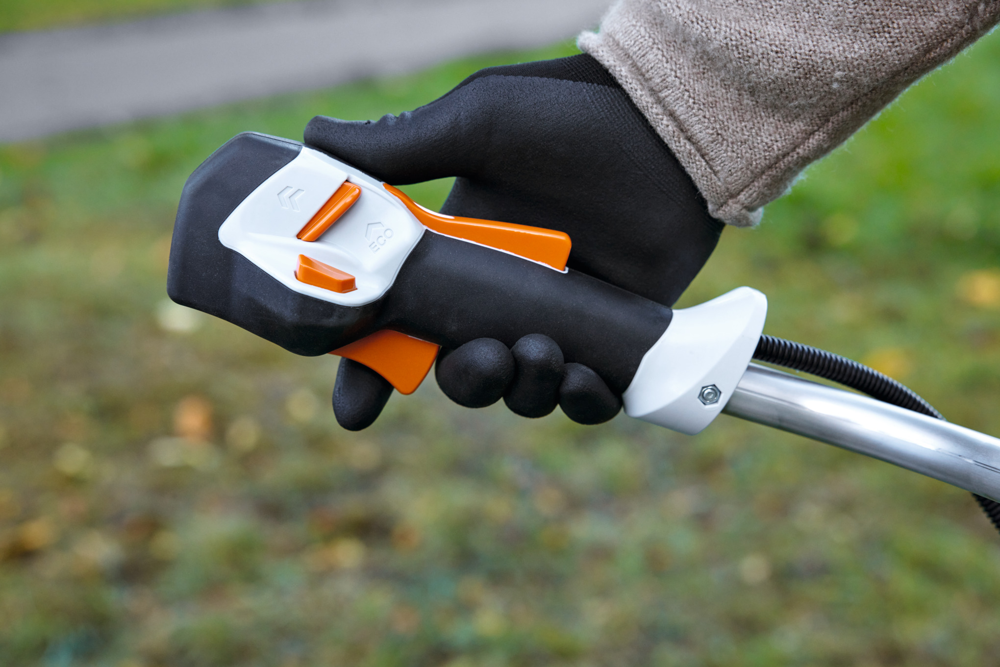 Hand in Handschuh hält Bediengriff einer STIHL FSA 120 Akku-Motorsense mit Geschwindigkeitsregulierung