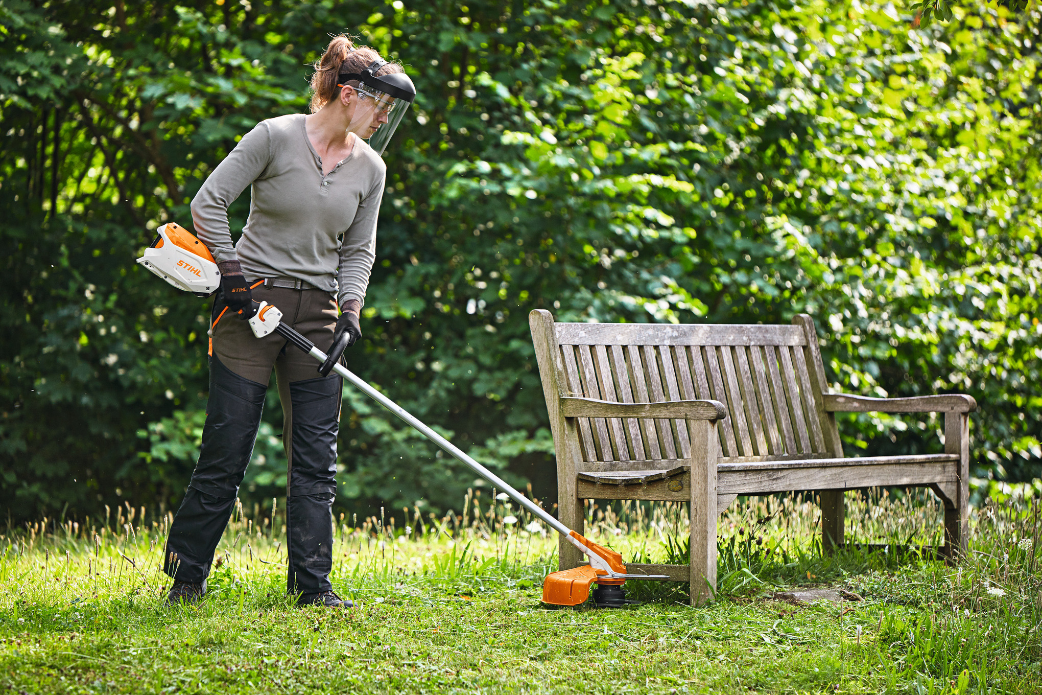 Frau benutzt STIHL Akku-Motorsense im Garten