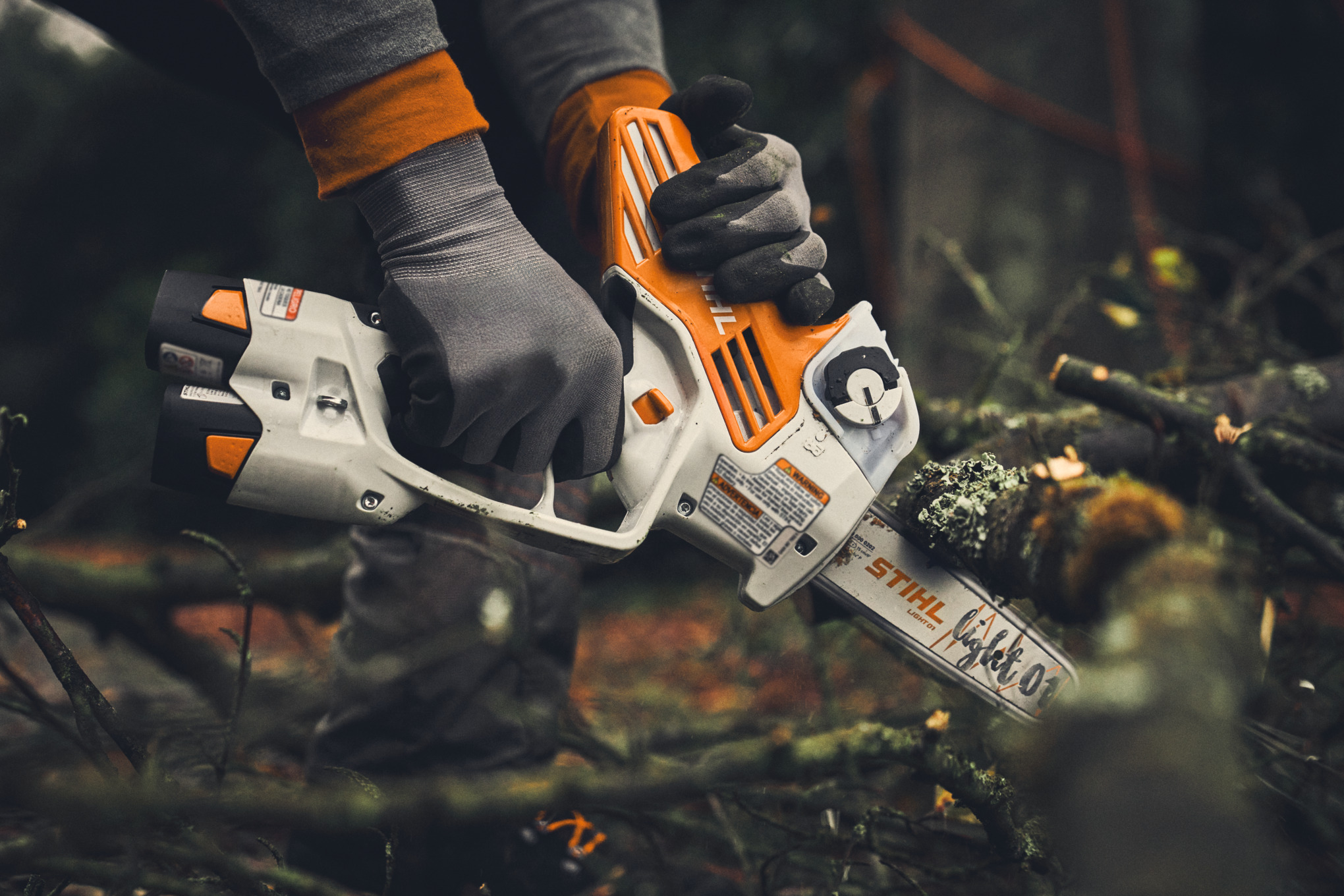 Person verwendet STIHL GTA 40 Motorsäge zum Schneiden eines Astes im Wald