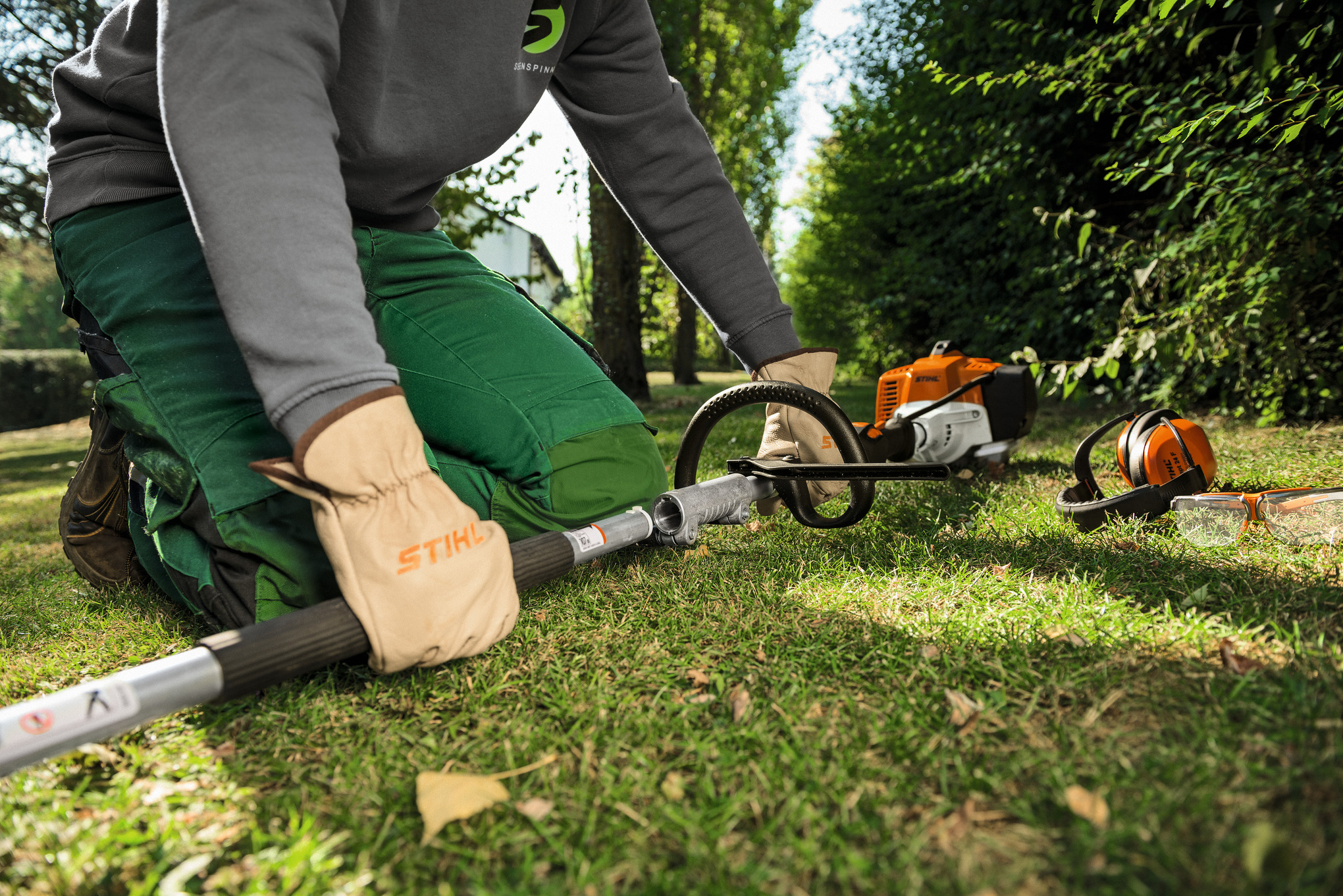 Person in Arbeitskleidung bedient STIHL KM 94 RC-E KombiMotor im Garten