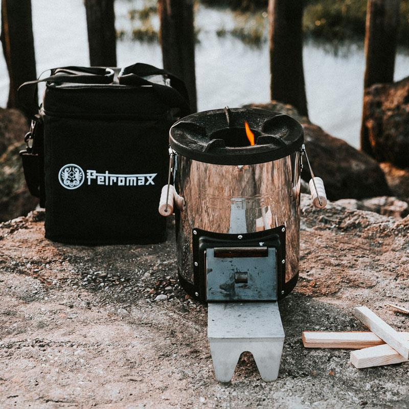 Petromax Raketenofen rf33 brennt neben seiner Transporttasche am Seeufer