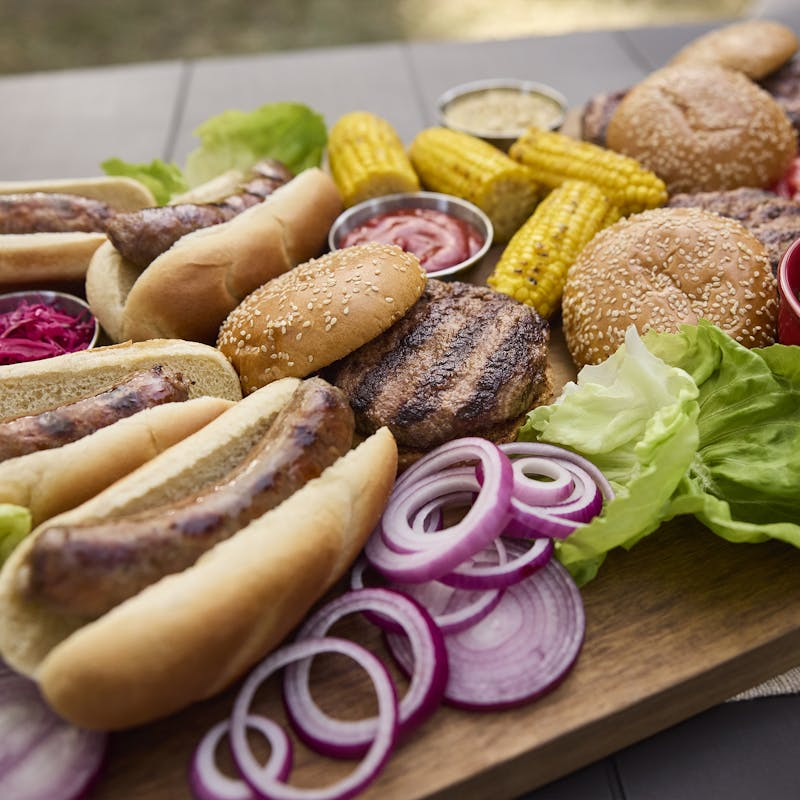 Appetitliche Auswahl an Grillgerichten auf einem Holzbrett im Freien