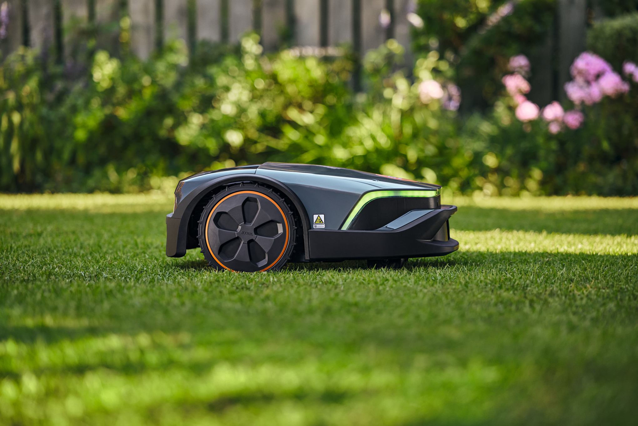 STIHL iMOW 7 EVO Mähroboter auf grünem Rasen mit Gartenhintergrund