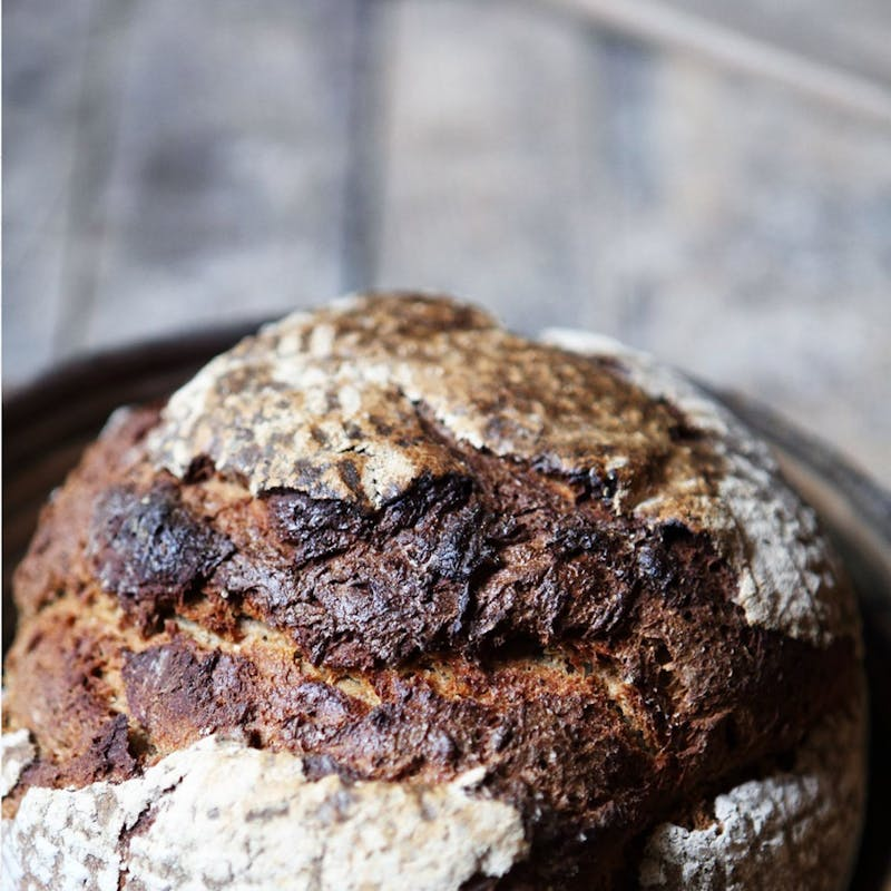 Rustikales dunkles Brot mit knuspriger Kruste auf holzähnlicher Oberfläche