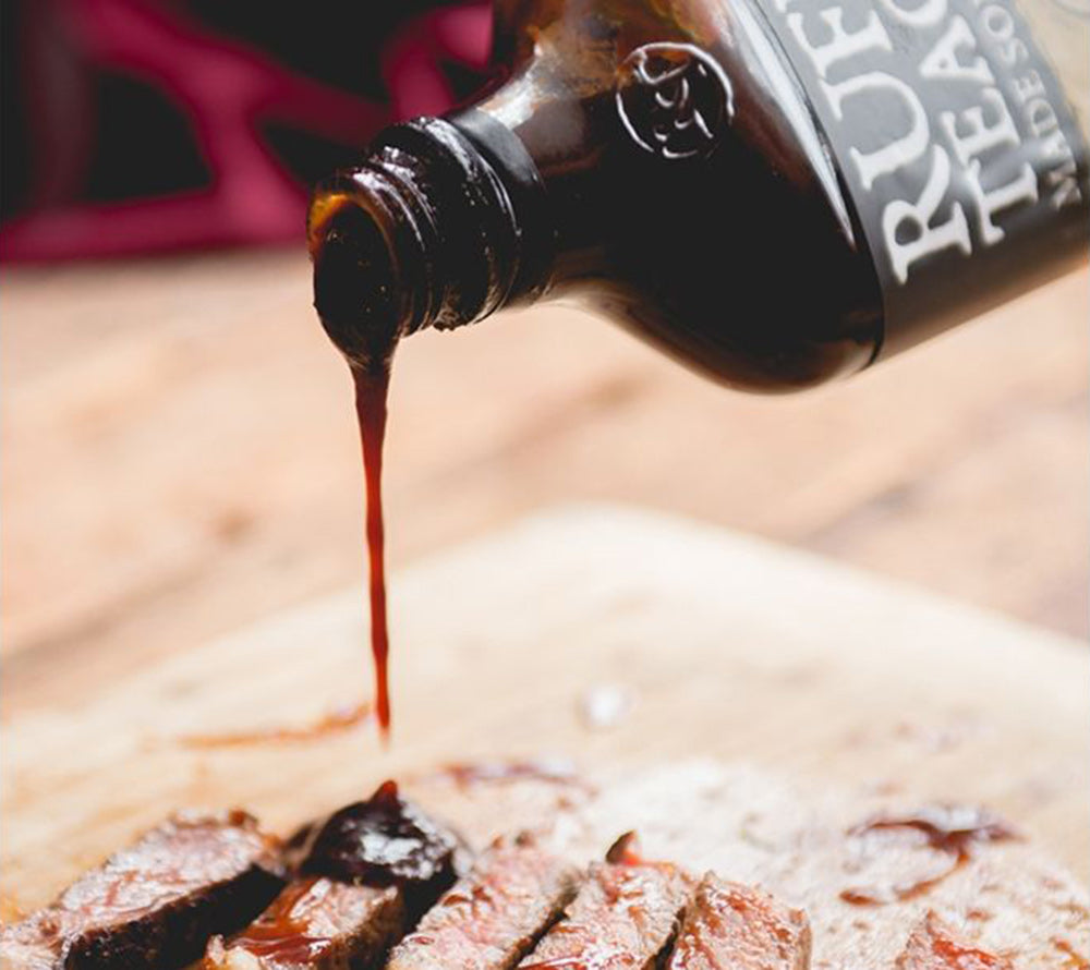 BBQ-Sauce wird aus Flasche auf gegrilltes Fleisch geträufelt