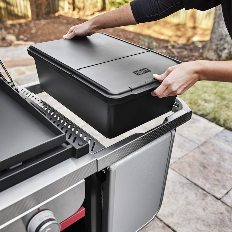 Person schließt witterungsbeständige Outdoor-Aufbewahrungsbox auf modernem Grilltisch