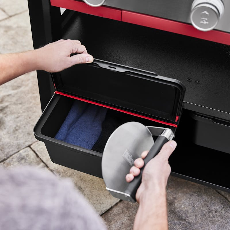 Person öffnet Outdoor-Aufbewahrungsbox und entnimmt Grillplatte