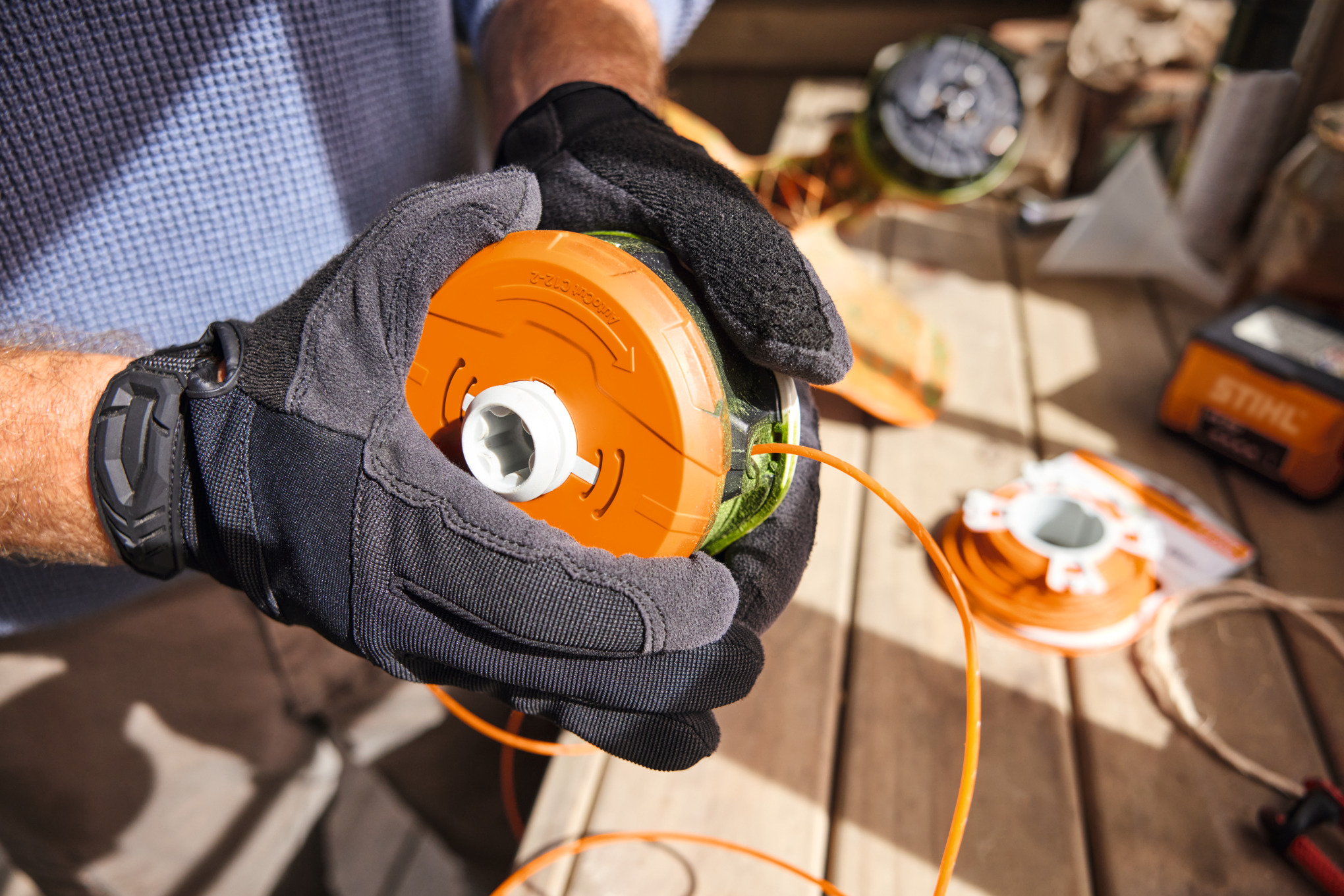 Person hält STIHL Mähkopf in Werkstatt
