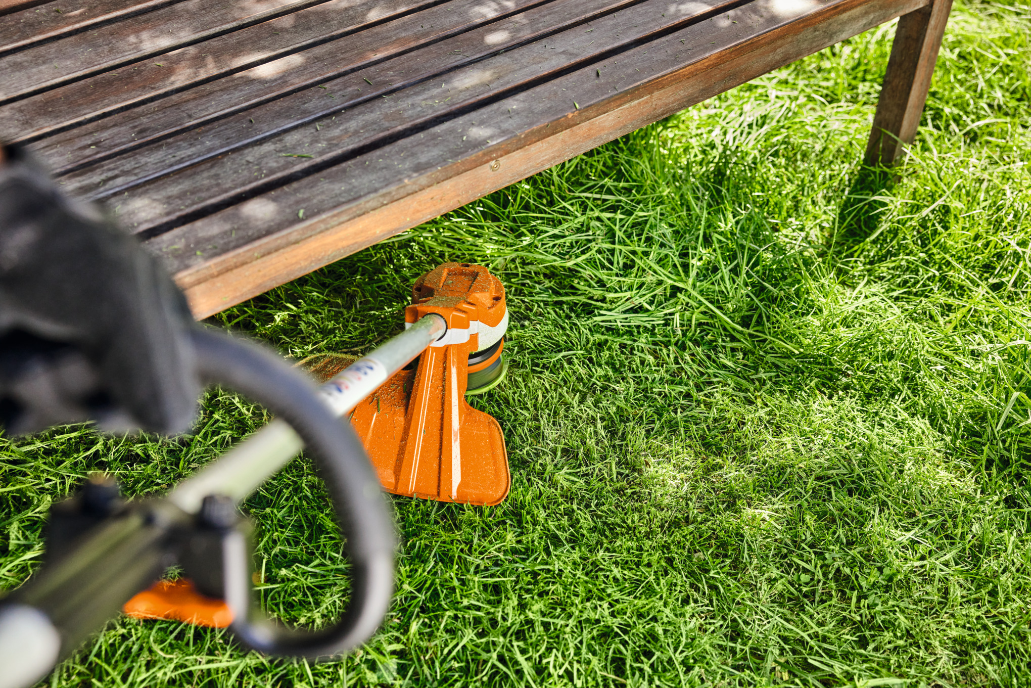 STIHL FSA 70 R Akku-Motorsense im Einsatz im Garten neben Holzmöbel