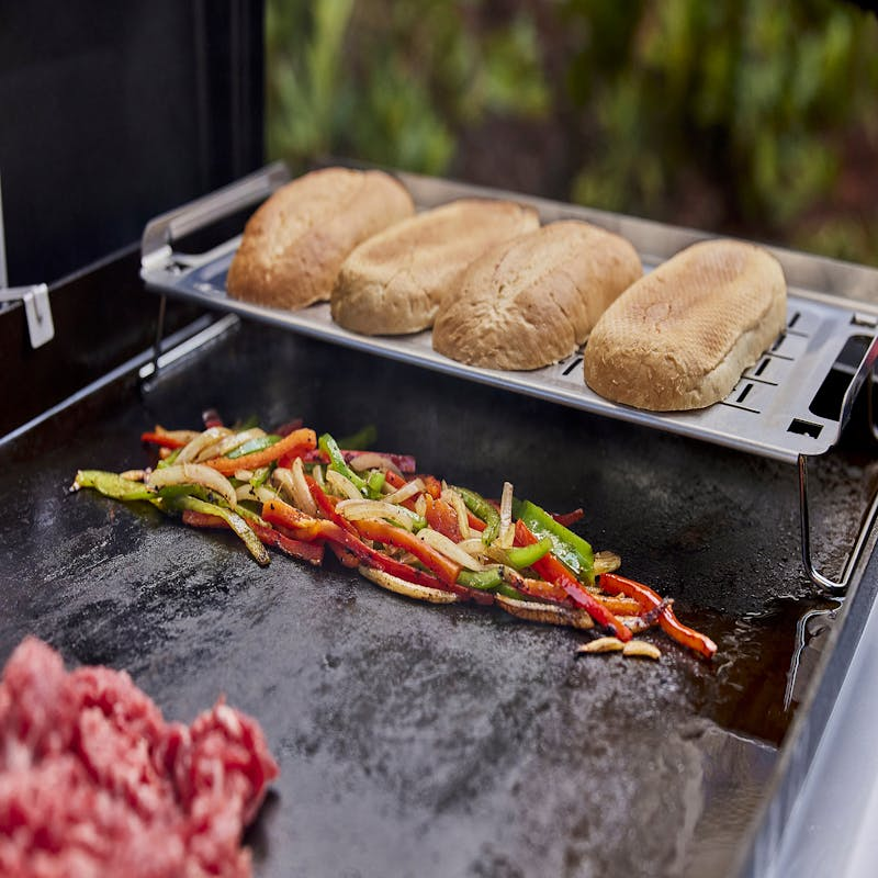 Weber Warmhalterost mit Brötchen und gegrilltem Gemüse auf einem Außengrill