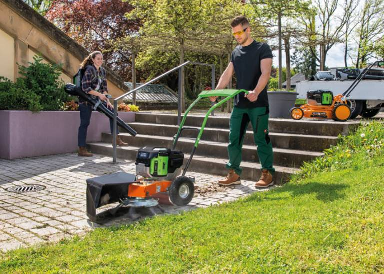 Mann und Frau bei Gartenarbeit mit Wildkrautentferner und Laubbläser