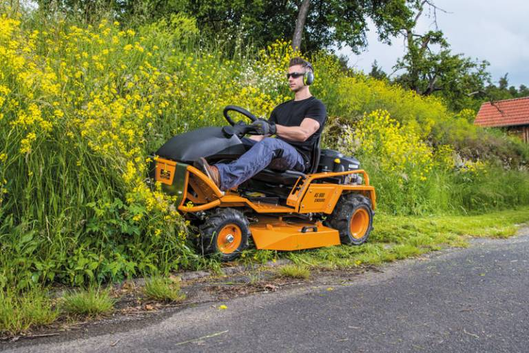 Mann fährt AS 900 Enduro Aufsitzmäher auf ländlicher Straße neben hohem Gras