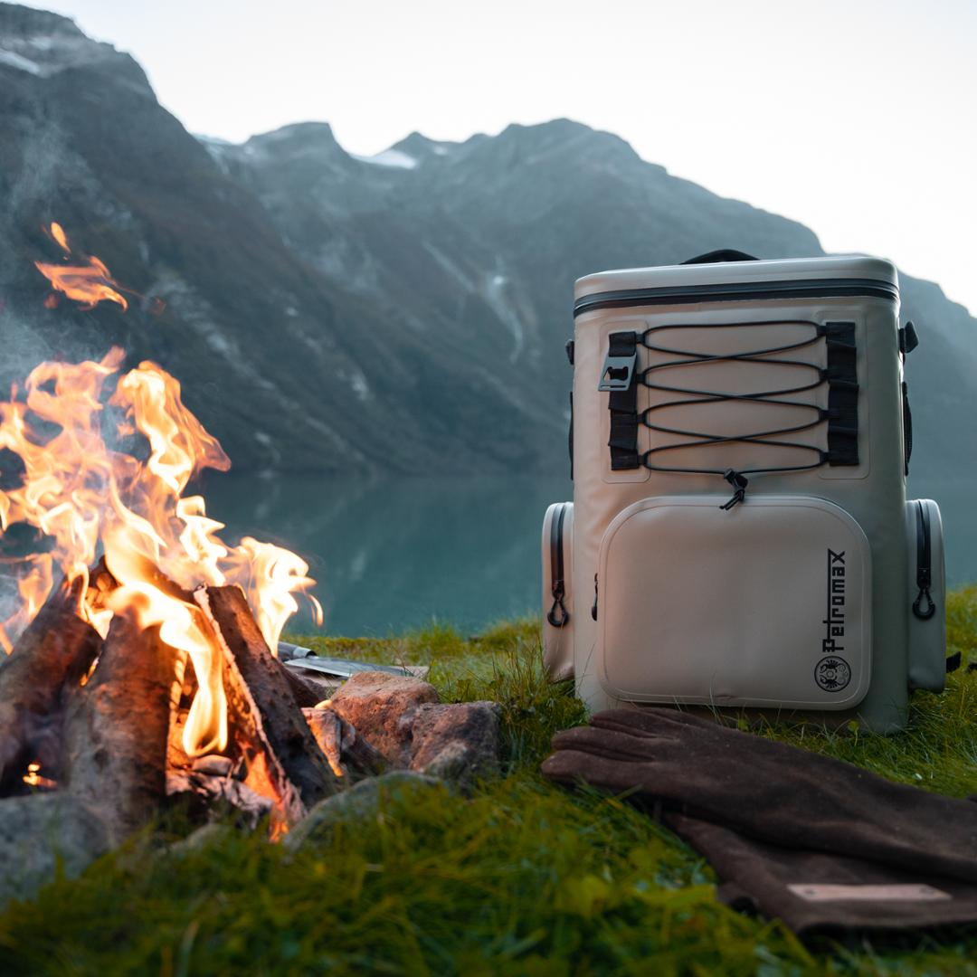 Petromax Kühlrucksack neben Lagerfeuer in Berglandschaft