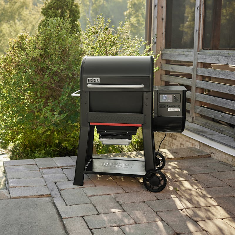 Weber SEARWOOD Holzpelletgrill in Schwarz auf einer Terrasse mit grüner Umgebung