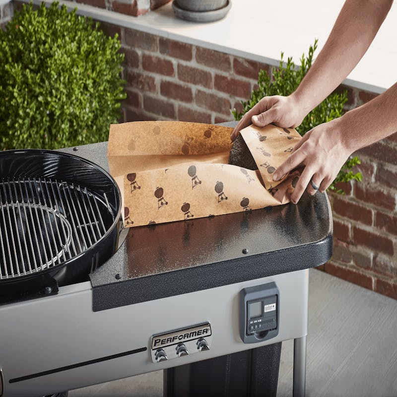 Person verwendet Weber Butcher Paper am Weber Performer Grill