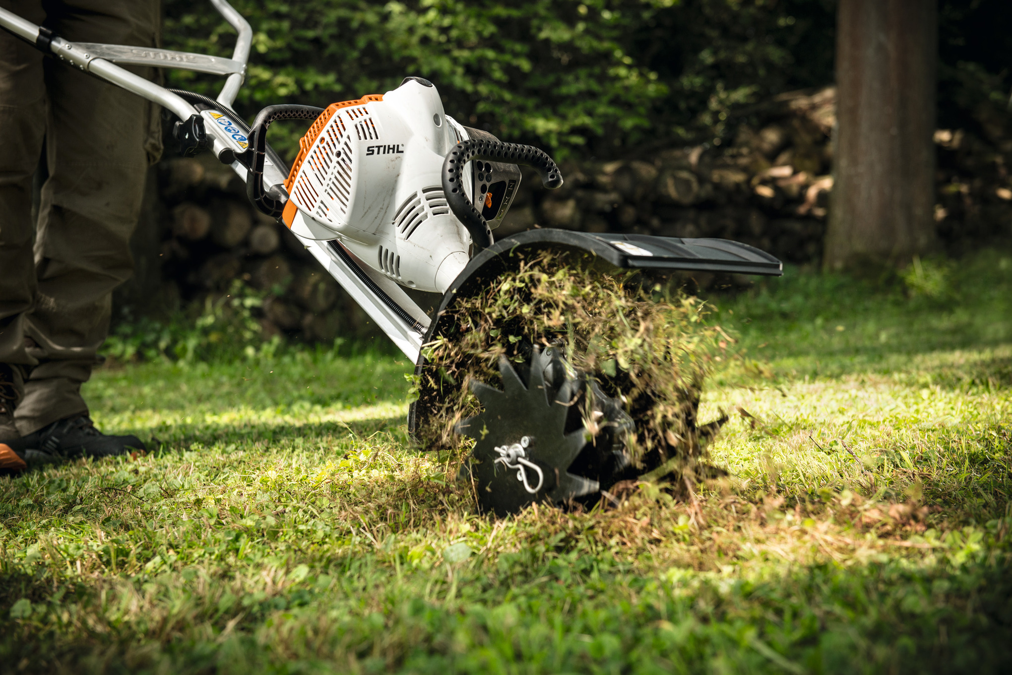 Stihl RL-MM Rasenlüfter in Aktion auf einem grünen Rasen mit aufgewirbeltem Gras und Erde