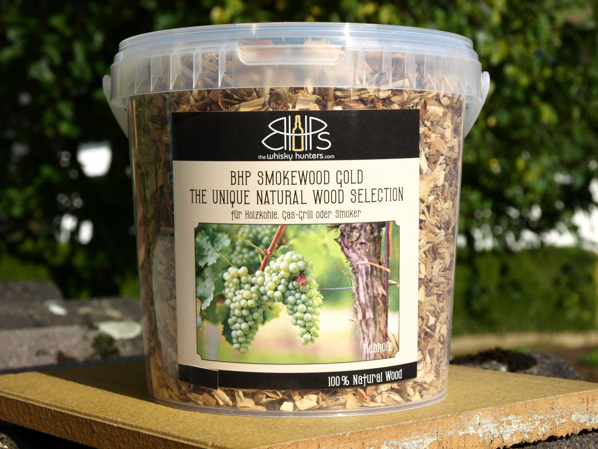 Transparente Box mit BHP Smokewood Gold Räucherchips auf Holzbrett im Freien