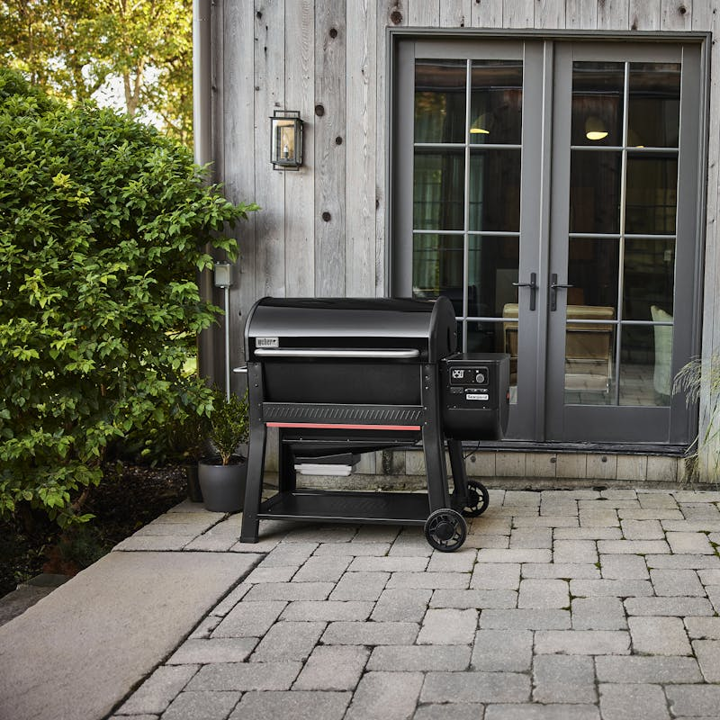 Weber SEARWOOD XL Holzpelletgrill vor einem modernen Haus mit Holzverkleidung